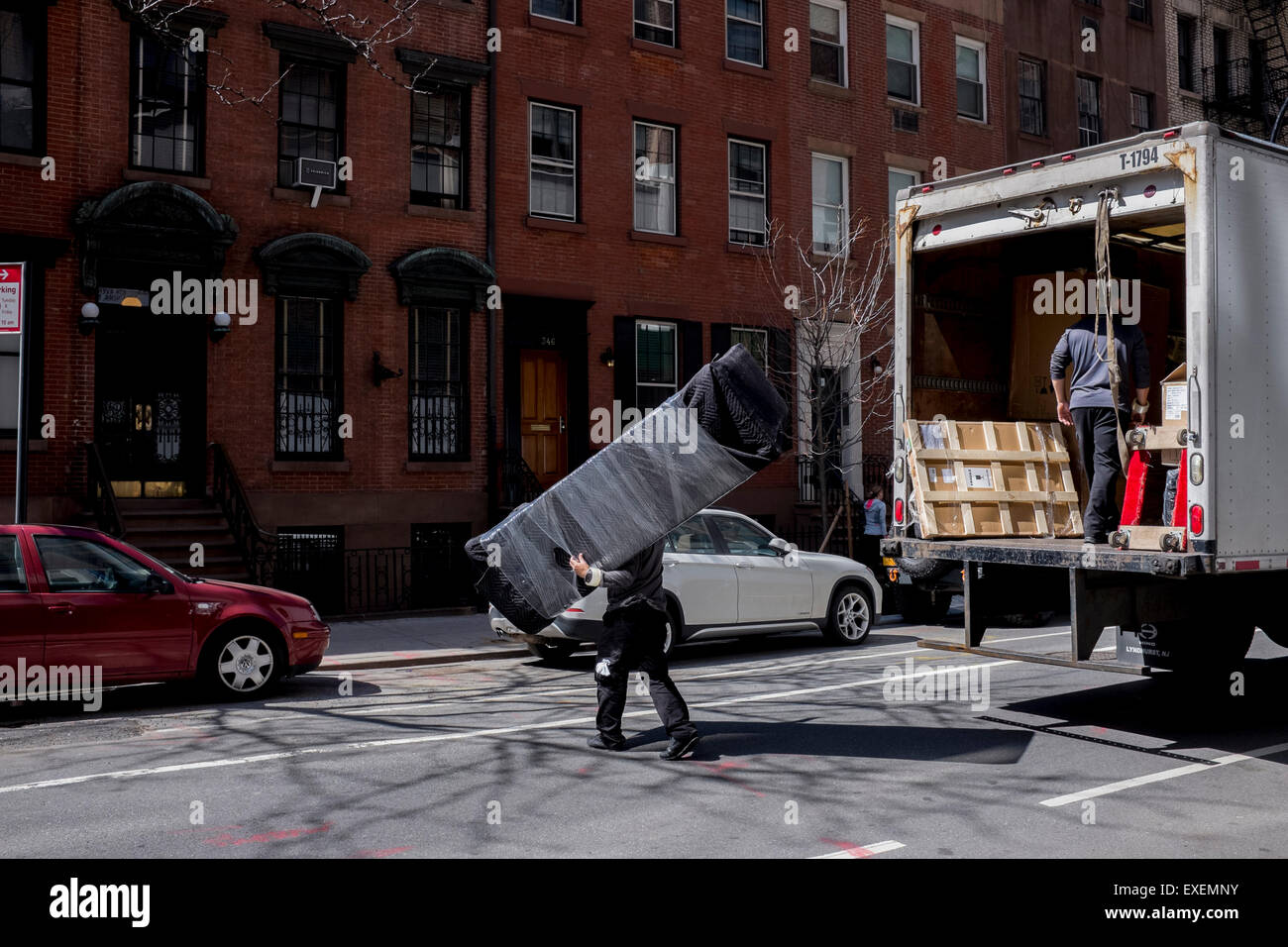 A man carries a sofa on moving day on Manhattan West Side in New York City Stock Photo