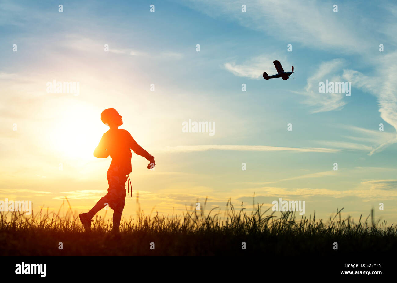 Boy throwing a model airplane at sunset. Silhouette Stock Photo