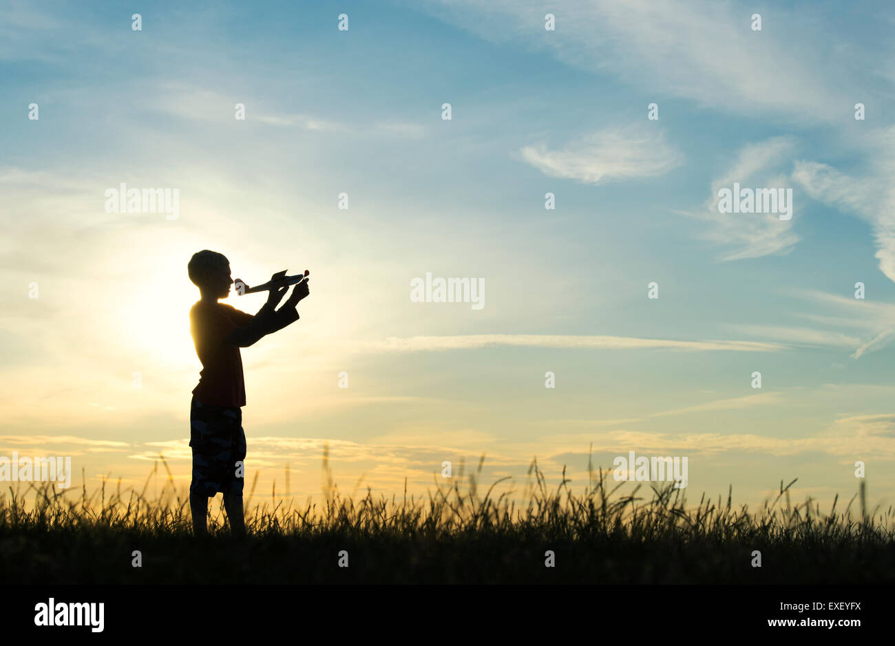 Boy throwing a model airplane at sunset. Silhouette Stock Photo