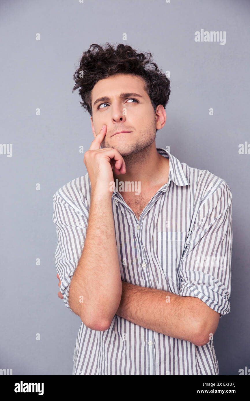 Portrait of a young pensive man looking away over gray background Stock Photo