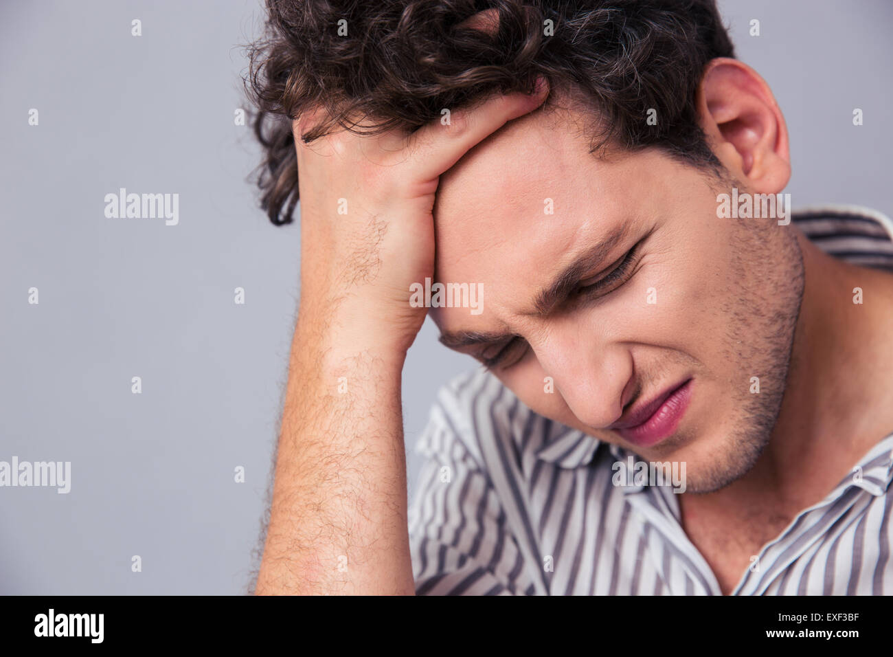 Closeup portrait of a stressed casual man over gray background Stock Photo