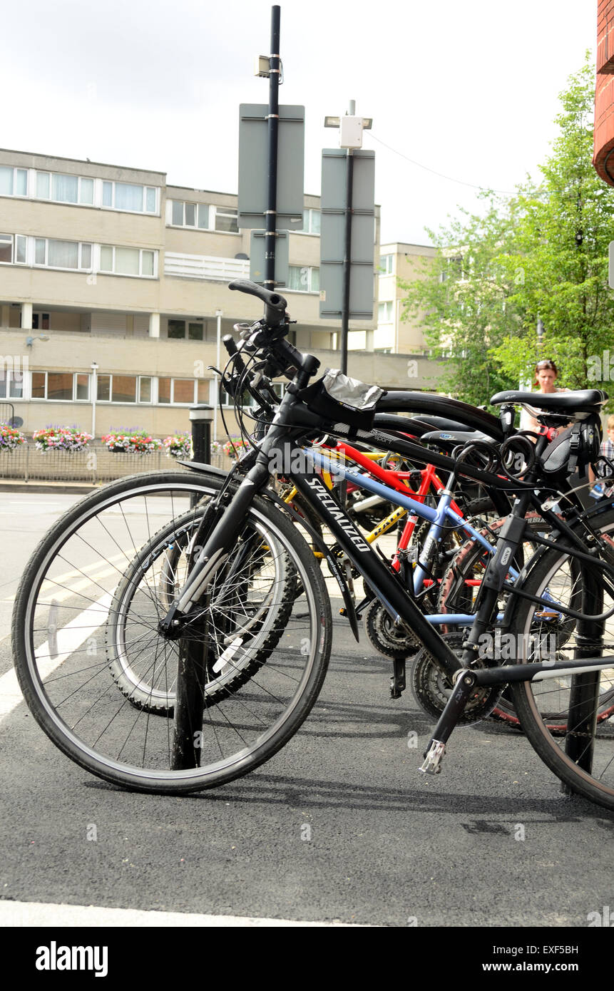 Bicycles fastened up at a bike rack. In the background are the flats at