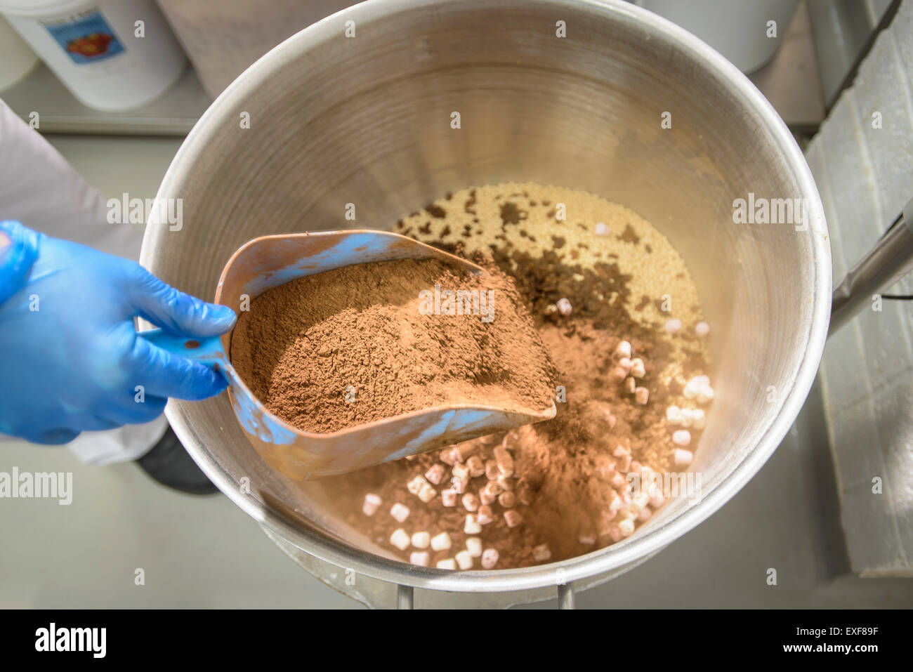 Cocoa powder being poured into cake mix in cake factory, close up Stock Photo