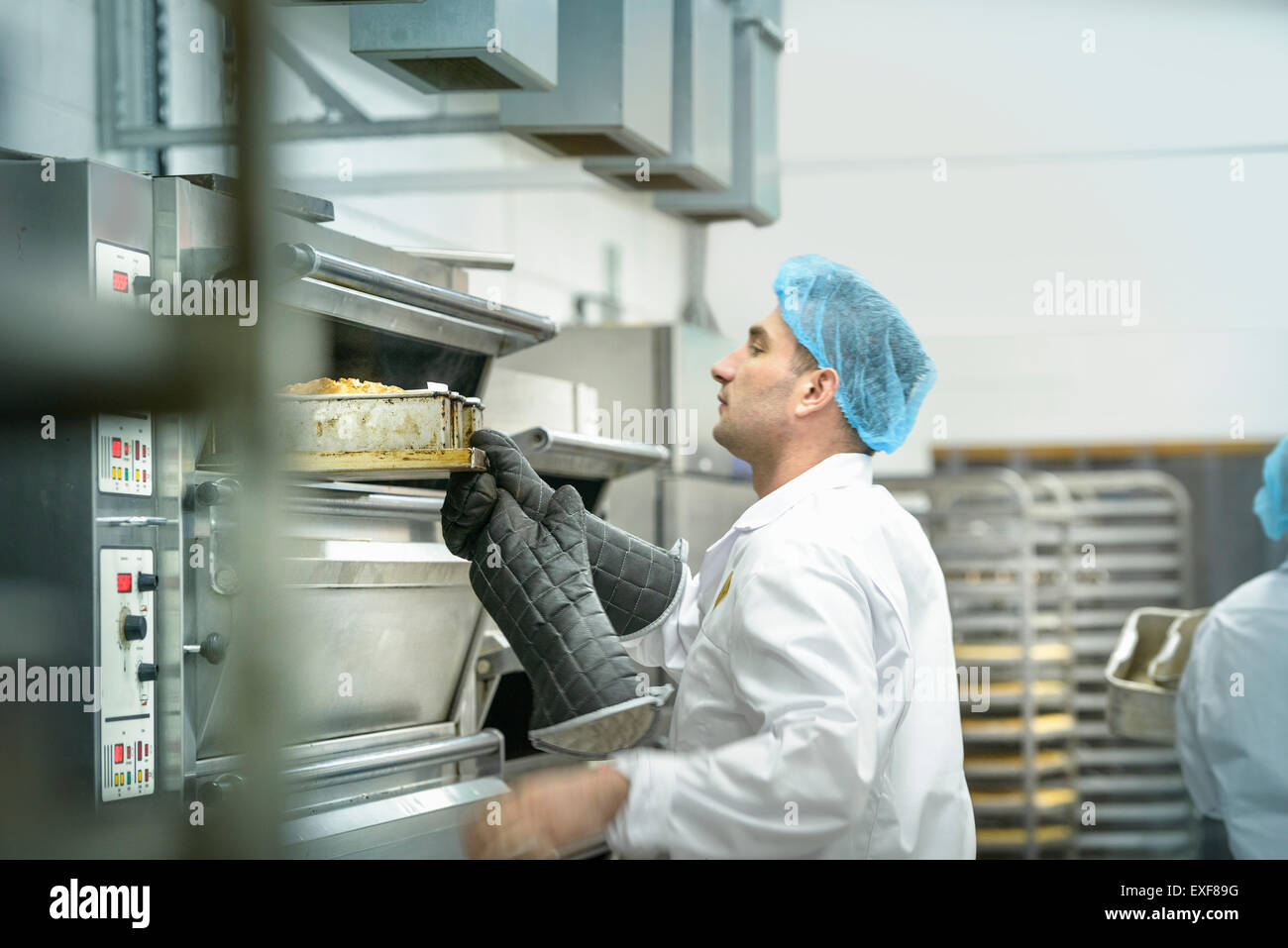 Baker inspecting cakes in oven in cake factory Stock Photo