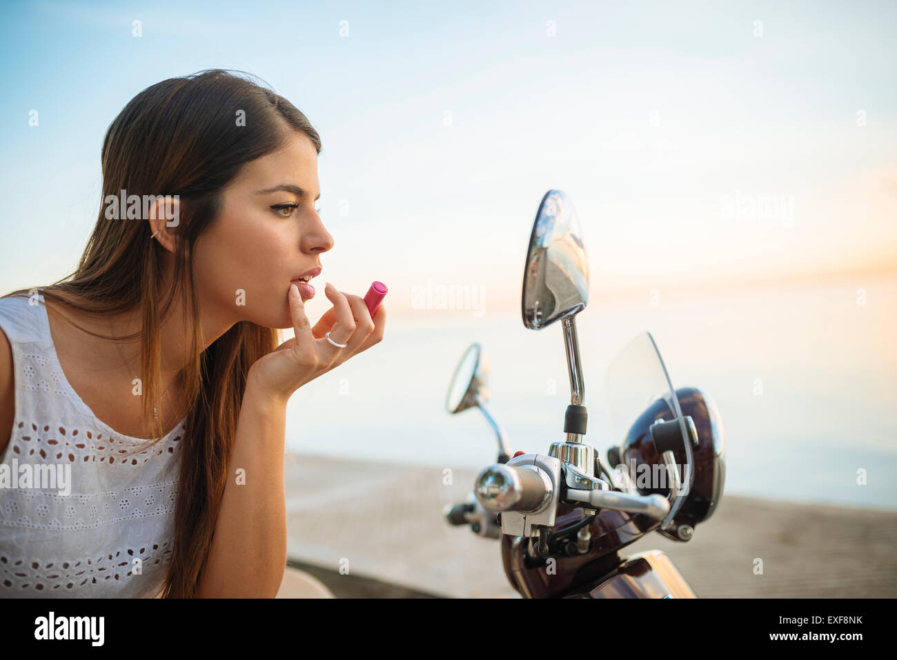 Young woman applying lipstick in motorcycle mirror, Manila, Philippines Stock Photo
