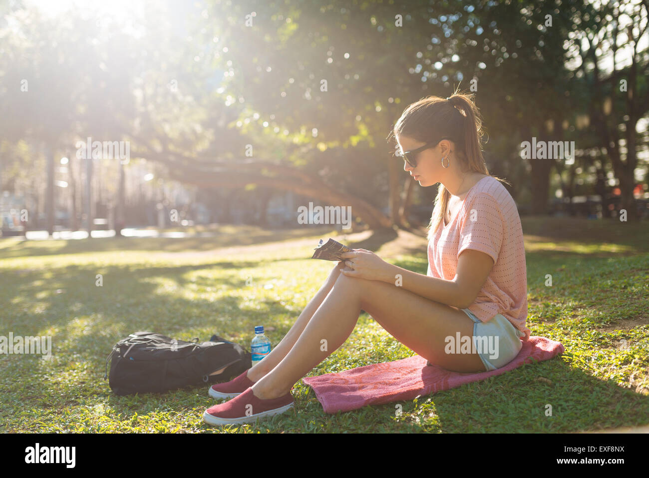 Young woman reading magazine in park, Manila, Philippines Stock Photo