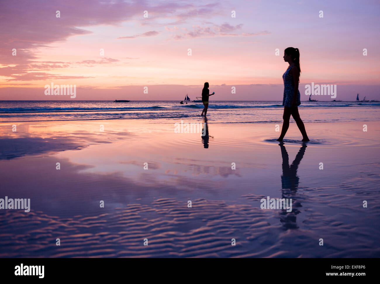 Silhouetted young woman strolling on beach at sunset, Boracay Island, Visayas, Philippines Stock Photo