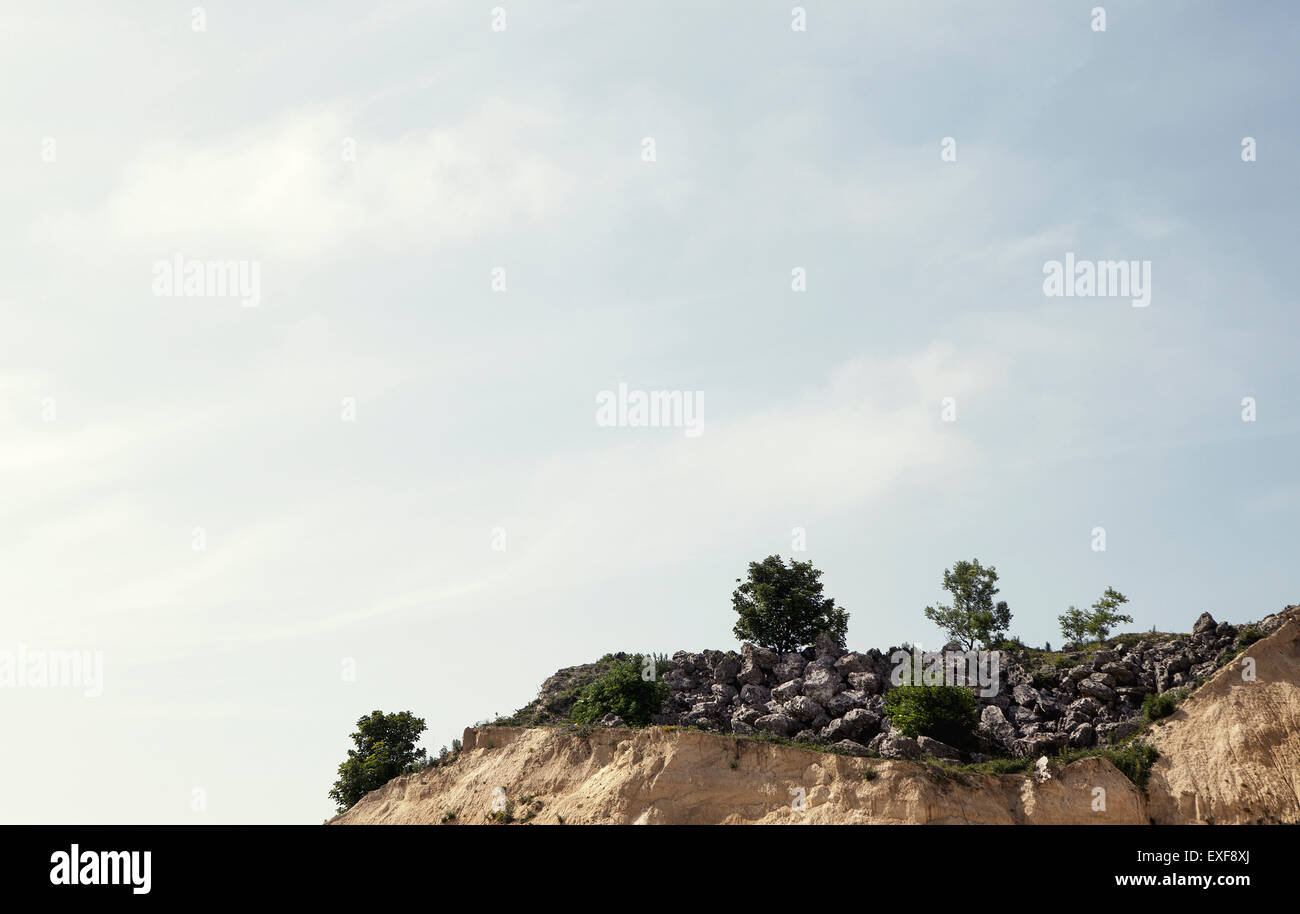 Abandoned quarry clifftop with rocks and bushes Stock Photo