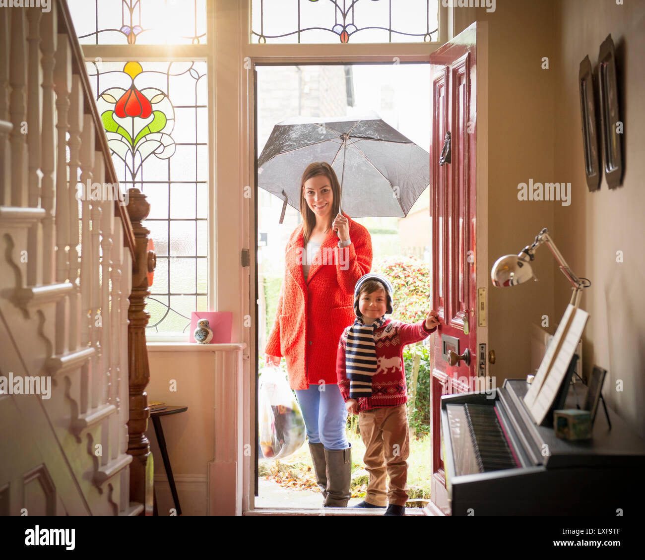 Mother and son arriving at front door of home on rainy day, portrait Stock Photo