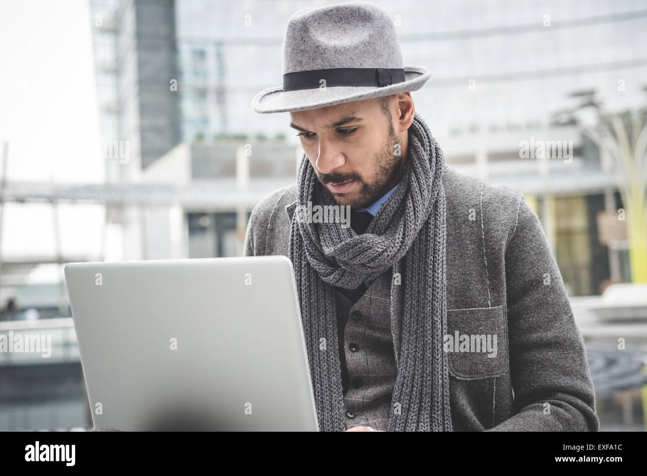 Businessman sitting outside office using laptop Stock Photo - Alamy