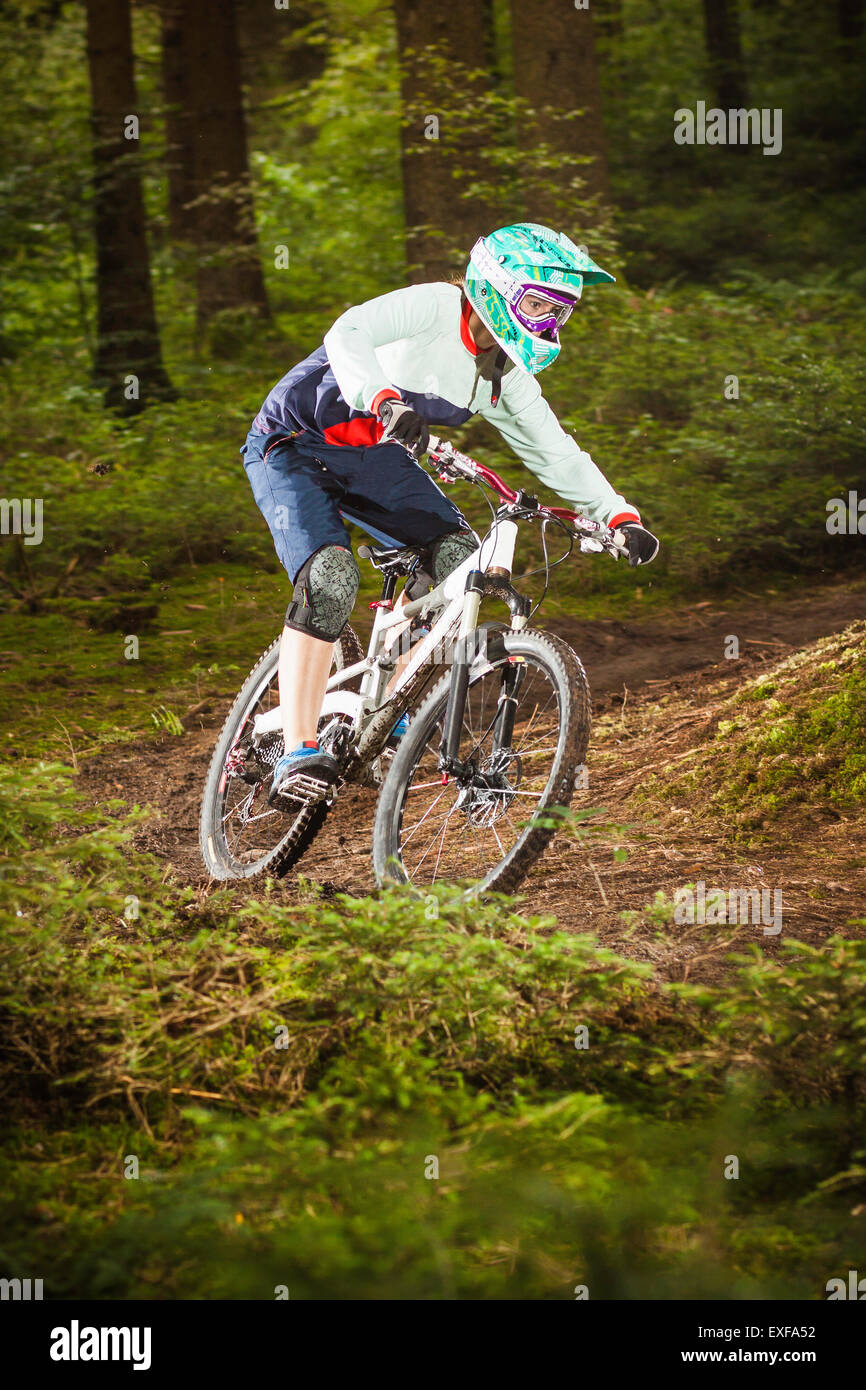 Young female downhill mountain biking in forest Stock Photo