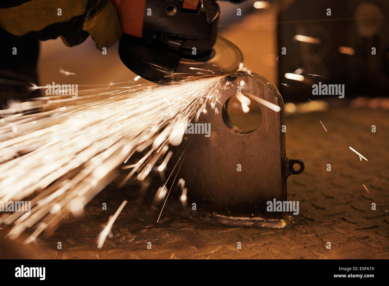 Sparks from worker using grinder in factory Stock Photo
