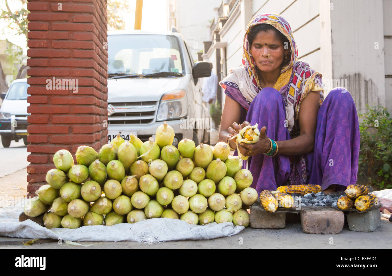 A woman selling roasted corns as a street vendor in Delhi, India Stock Photo