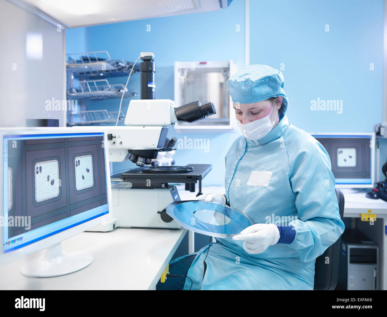 Electronics worker in clean room with silicon wafer Stock Photo