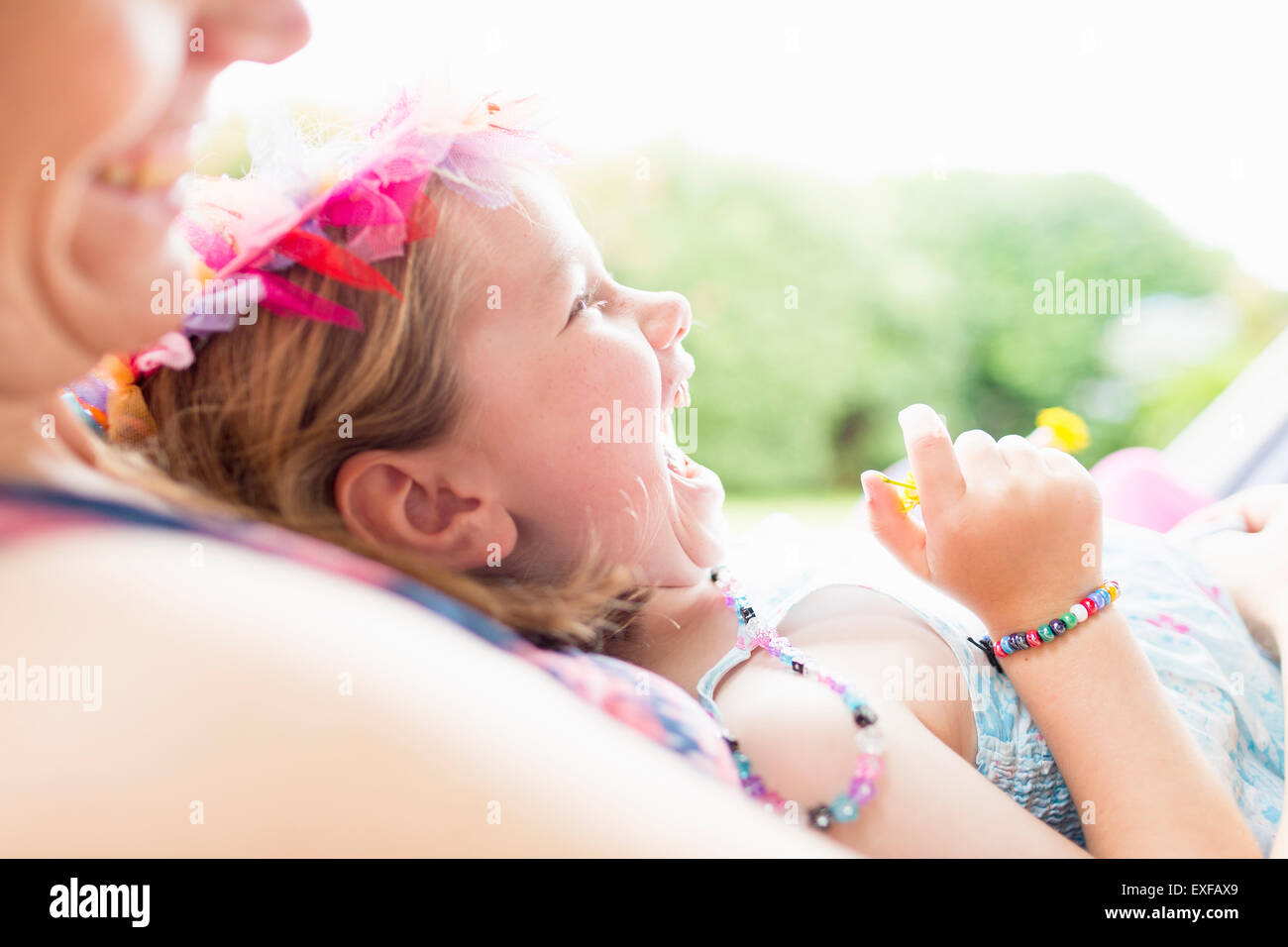 Daughter lying on mother's lap, laughing Stock Photo