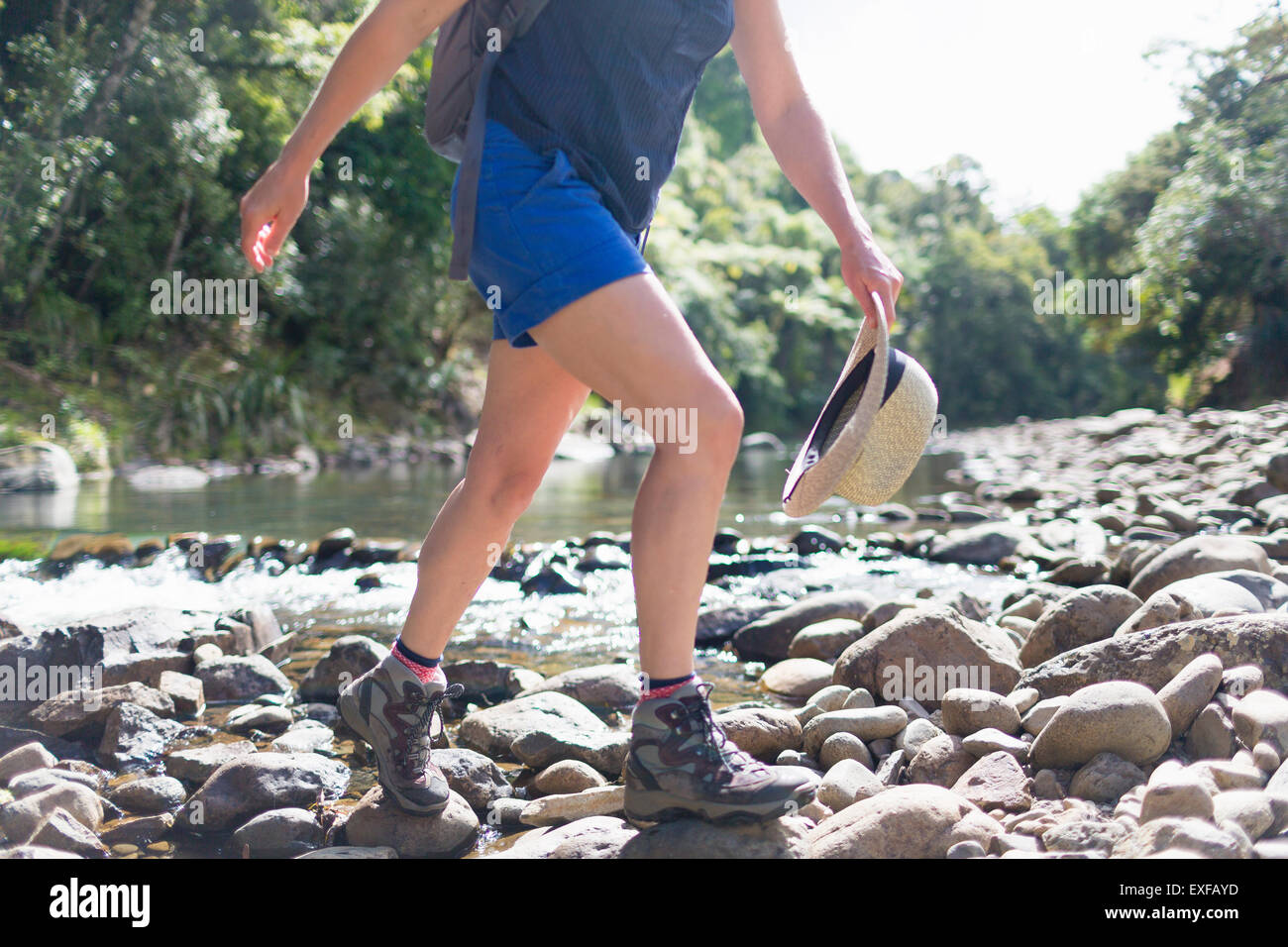Hiker walking among stones in shallow stream, Waima Forest, North Island, NZ Stock Photo
