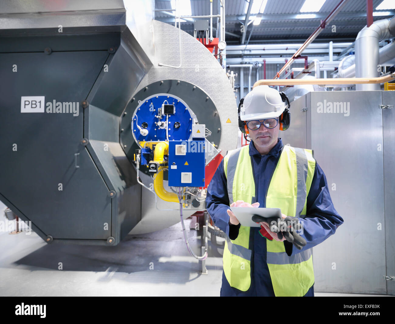 Worker checking readings on digital tablet in gas fired power station Stock Photo
