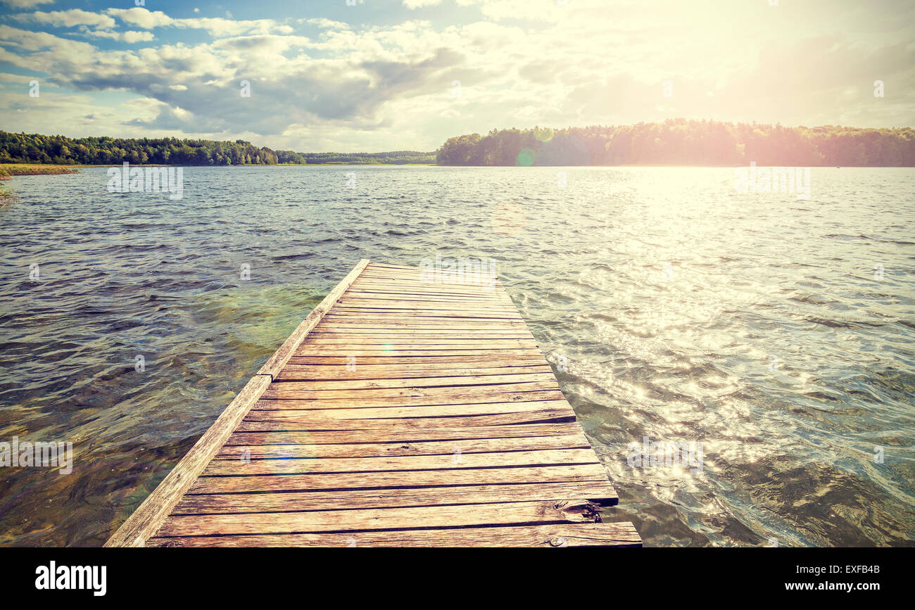 Retro style old wooden pier with flare effect at sunset. Stock Photo