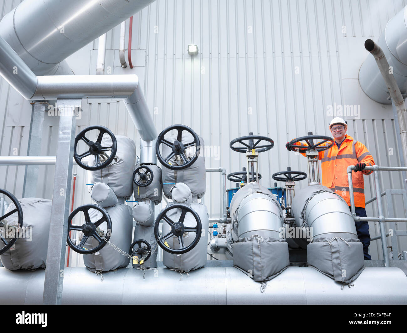 Worker standing by valves of gas fired power station Stock Photo