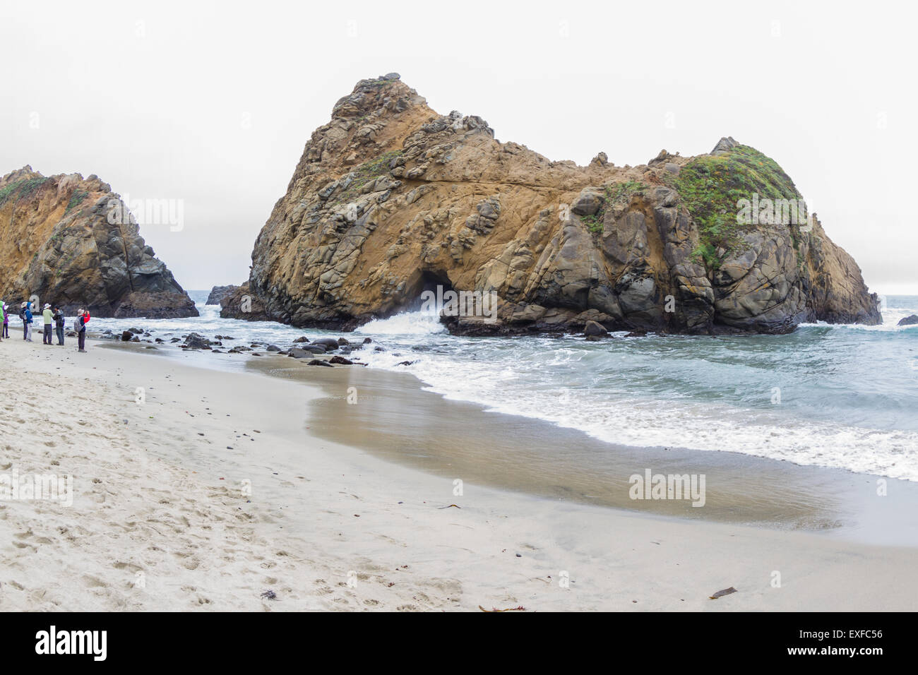 Large rock on the beach with a tunnel where the waves come in and out ...
