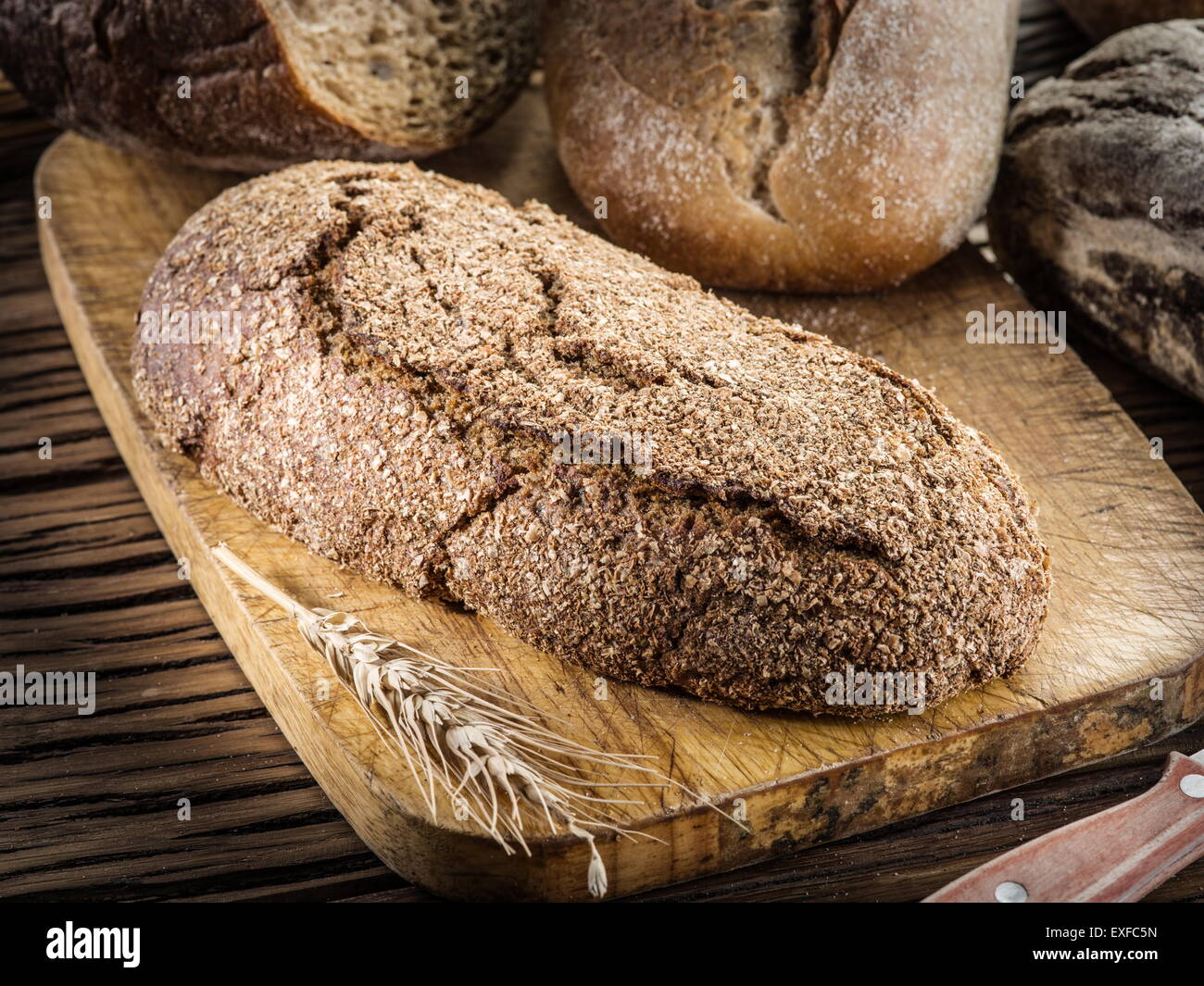 Long black loaf on the wooden plank. Stock Photo