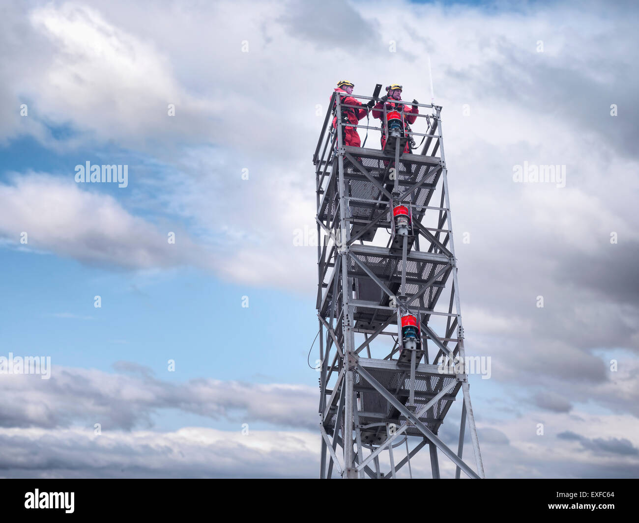 Two tower workers on offshore radio tower on windfarm, low angle view Stock Photo