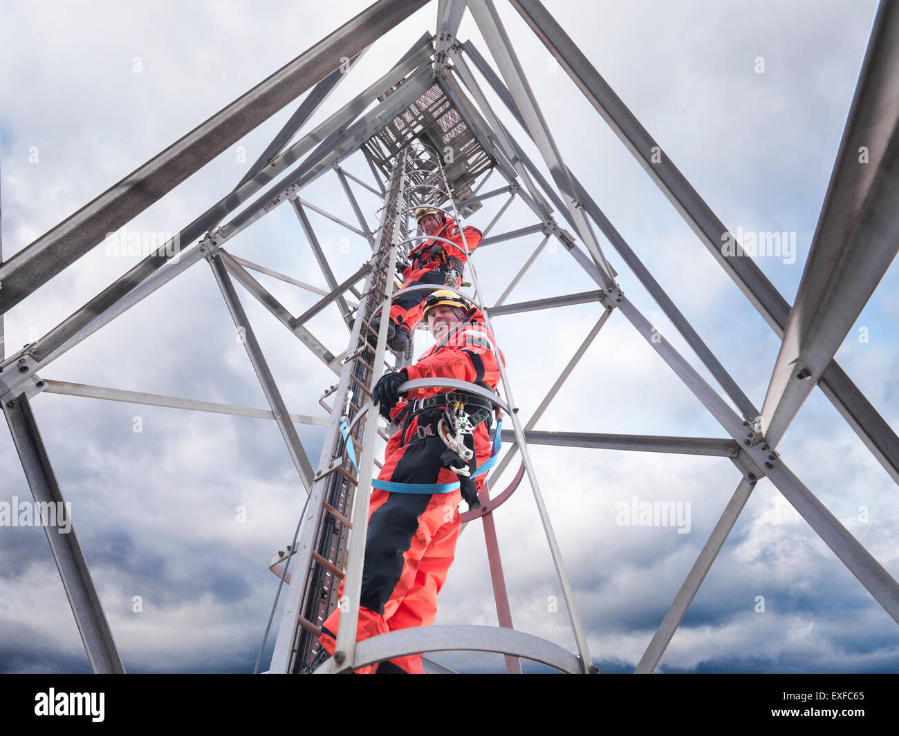 Tower workers climbing radio tower on offshore windfarm, low angle view Stock Photo