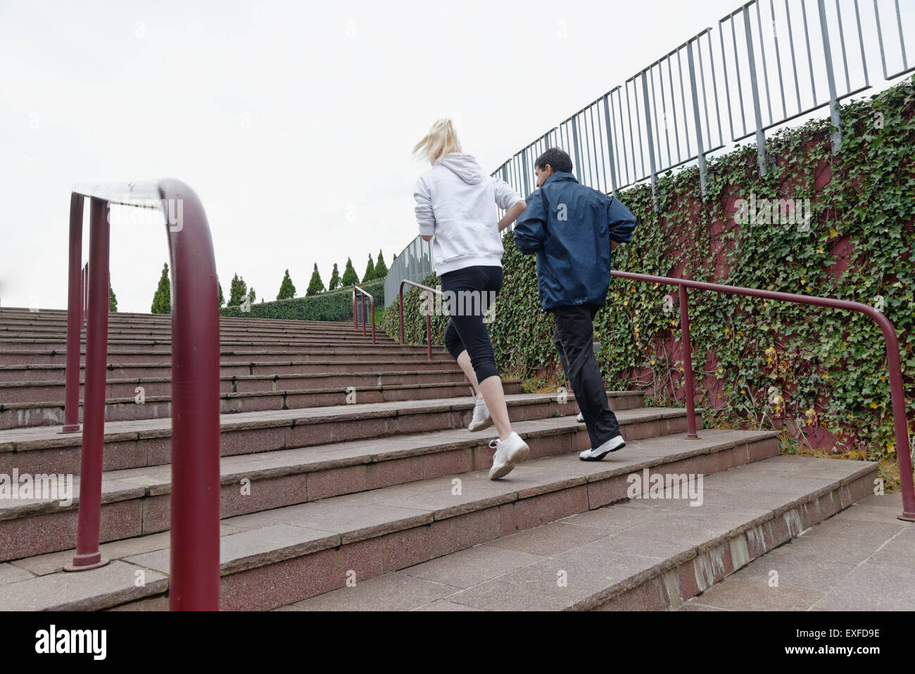 Man and woman running up steps together, rear view Stock Photo