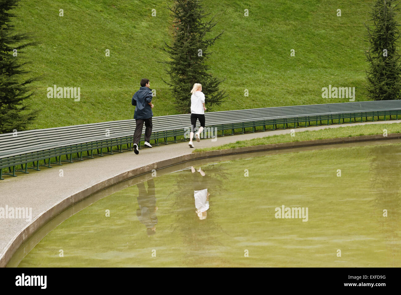 Man and woman running beside lake, rear view Stock Photo