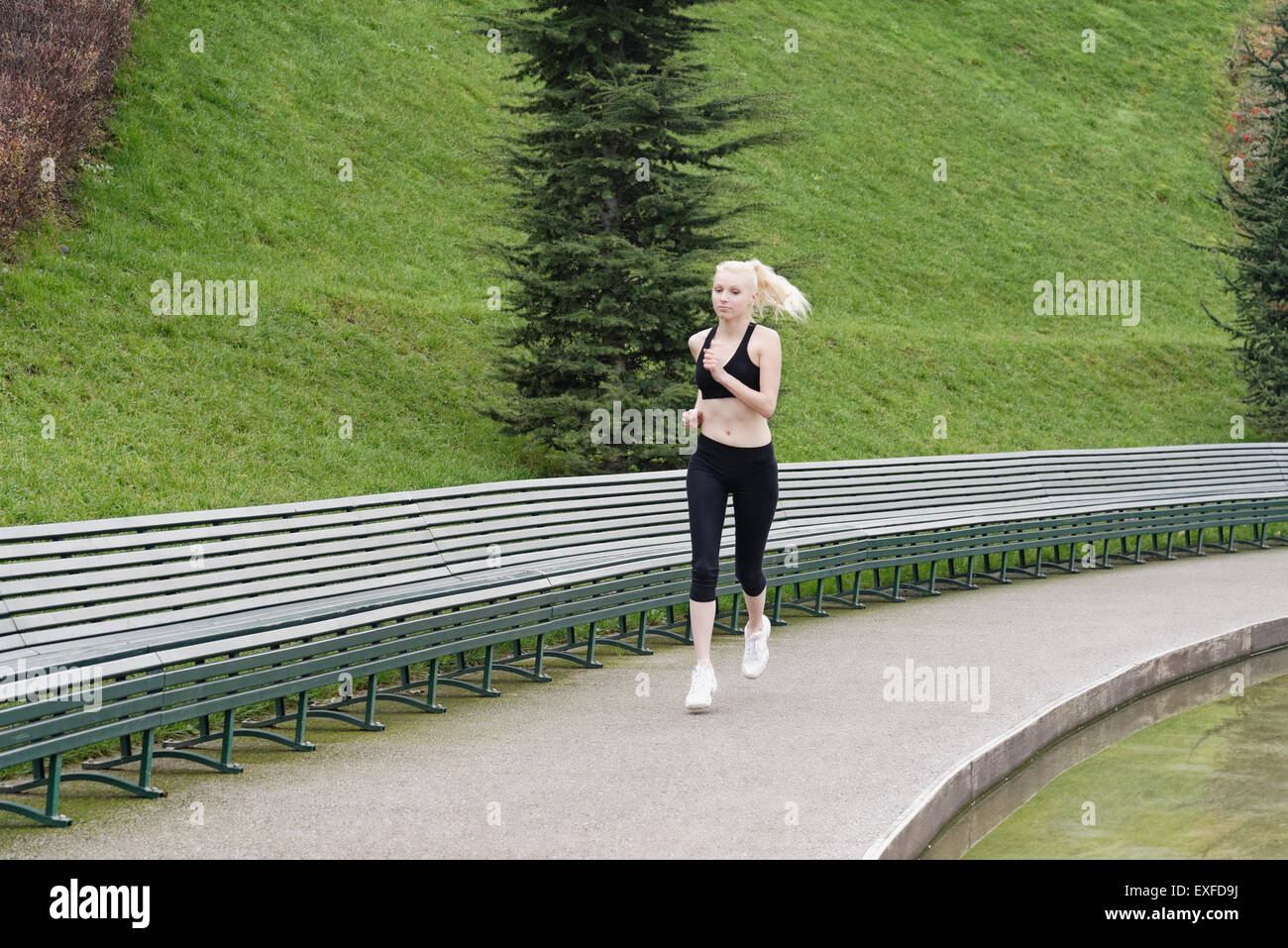 Young woman running beside lake Stock Photo
