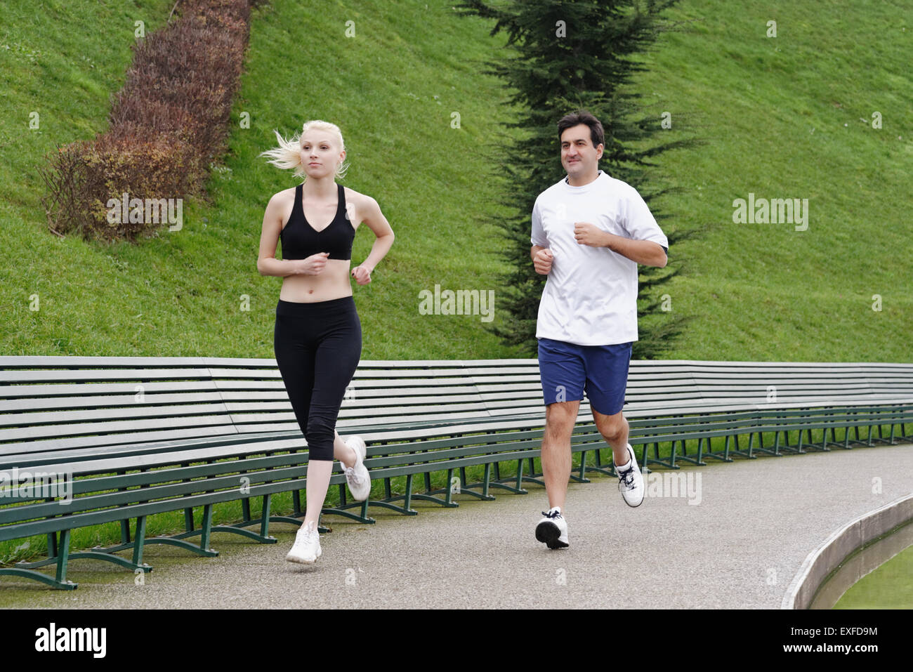 Man and woman running on pathway beside lake Stock Photo