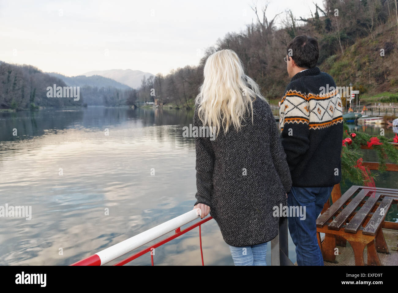 Heterosexual couple standing beside lake, Lombardy, Italy, rear view Stock Photo