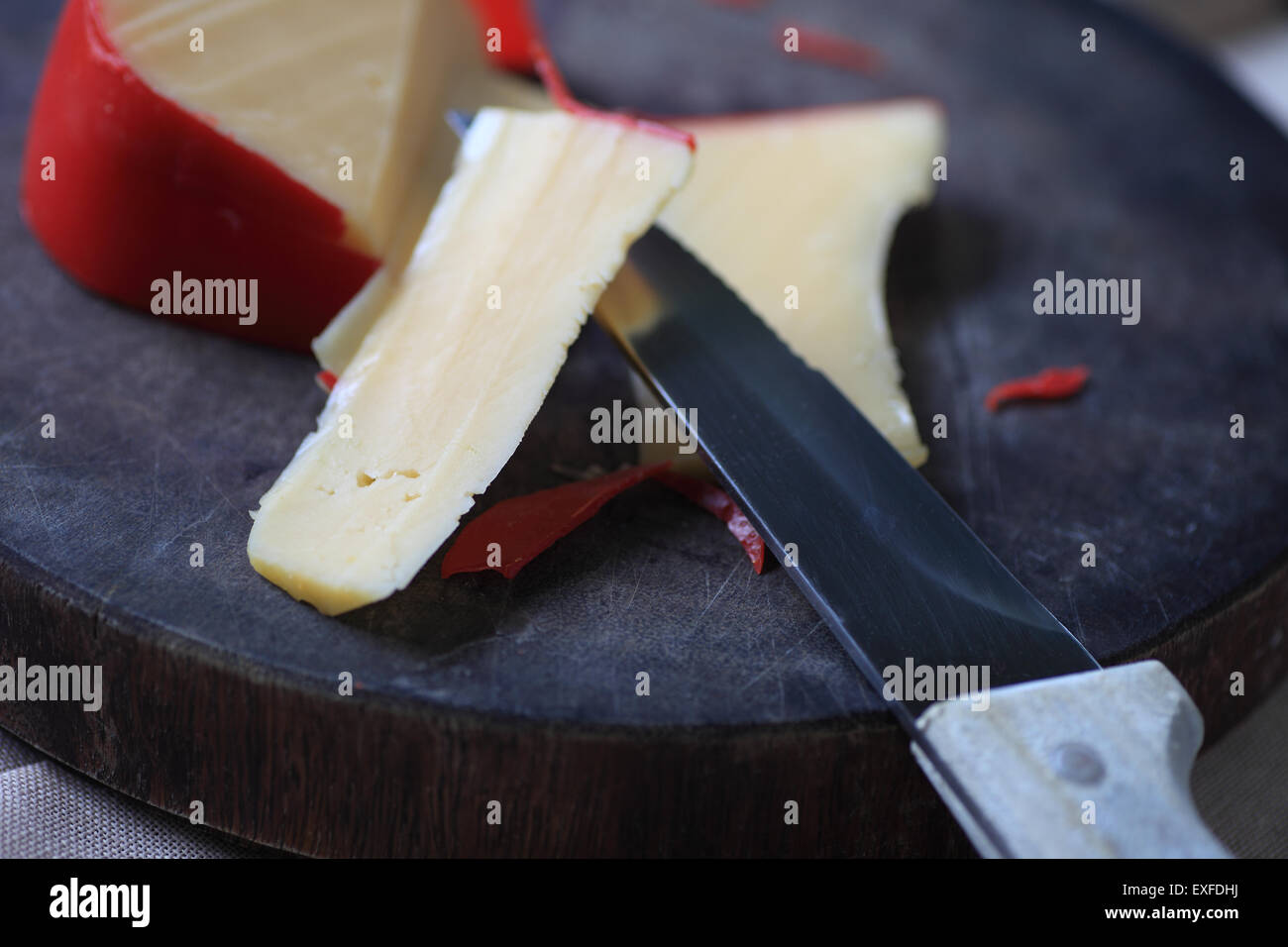 A block of cheese on a cutting board, slices cut Stock Photo