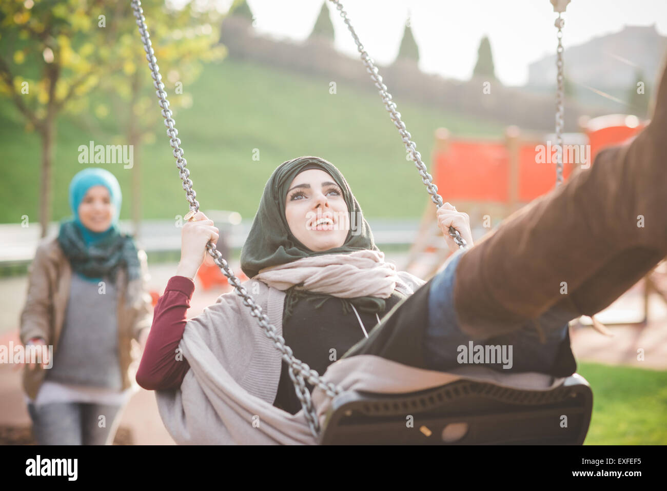 Young Women Swinging On Playground Swing Stock Photo