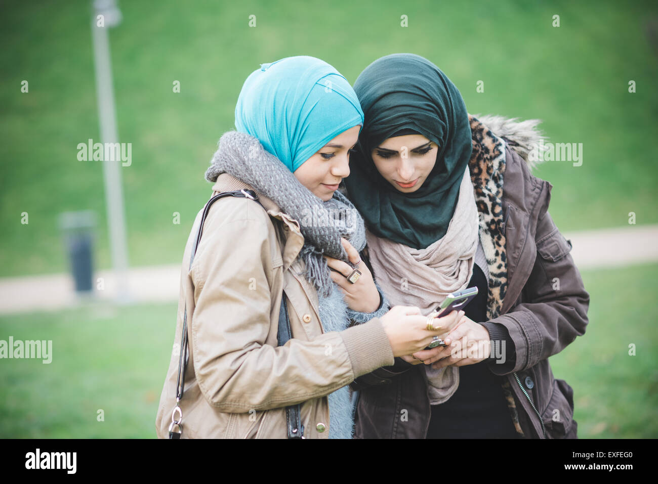 Two female friends in park reading text on smartphones Stock Photo