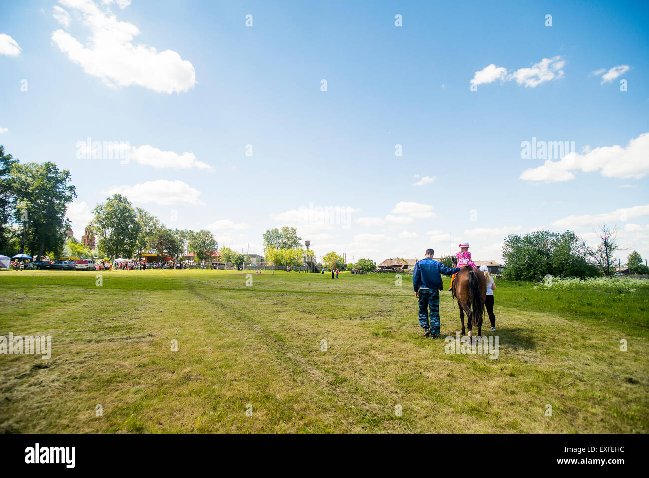 Rear view of young man and two girls riding horse in field, Rezh, Sverdlovsk Oblast, Russia Stock Photo