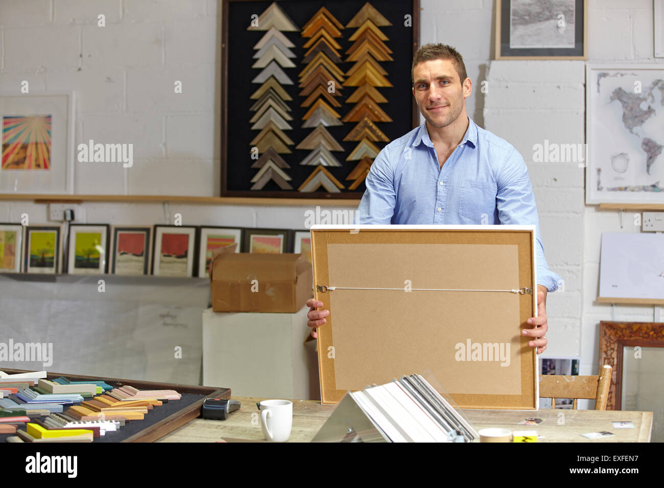 Portrait of framer holding finished picture in picture framers