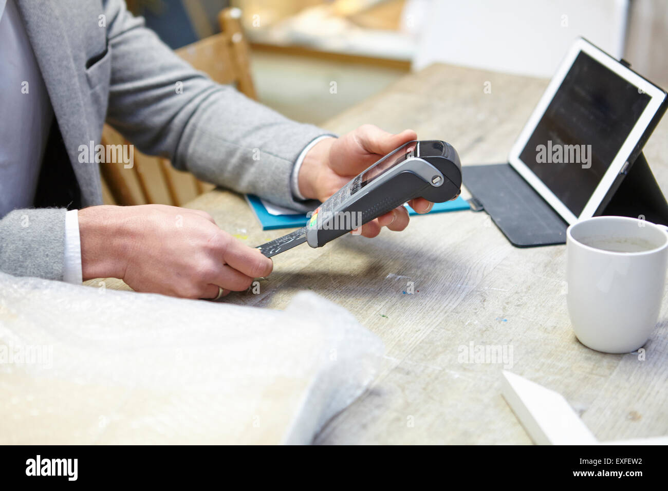Man buying online with credit card in picture framers workshop Stock Photo