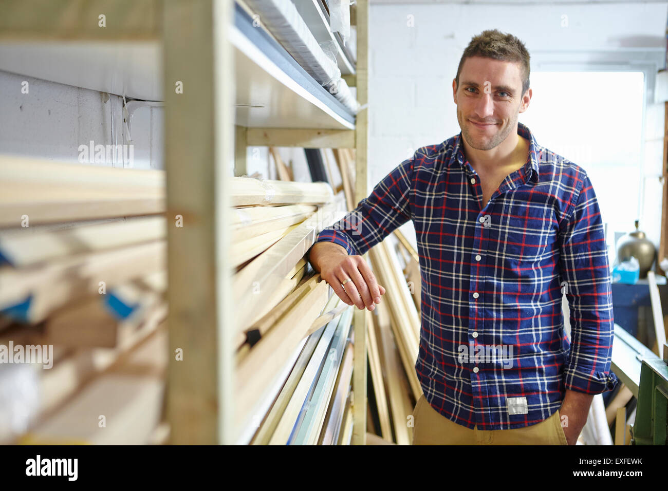 Portrait of mid adult man leaning against shelves in picture framers workshop Stock Photo