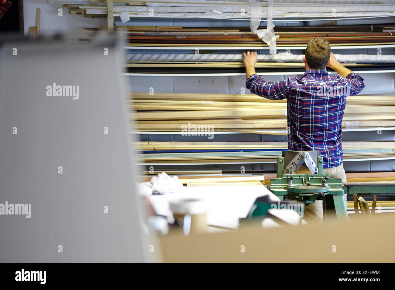 Rear view of man searching stockroom shelves in picture framers workshop Stock Photo