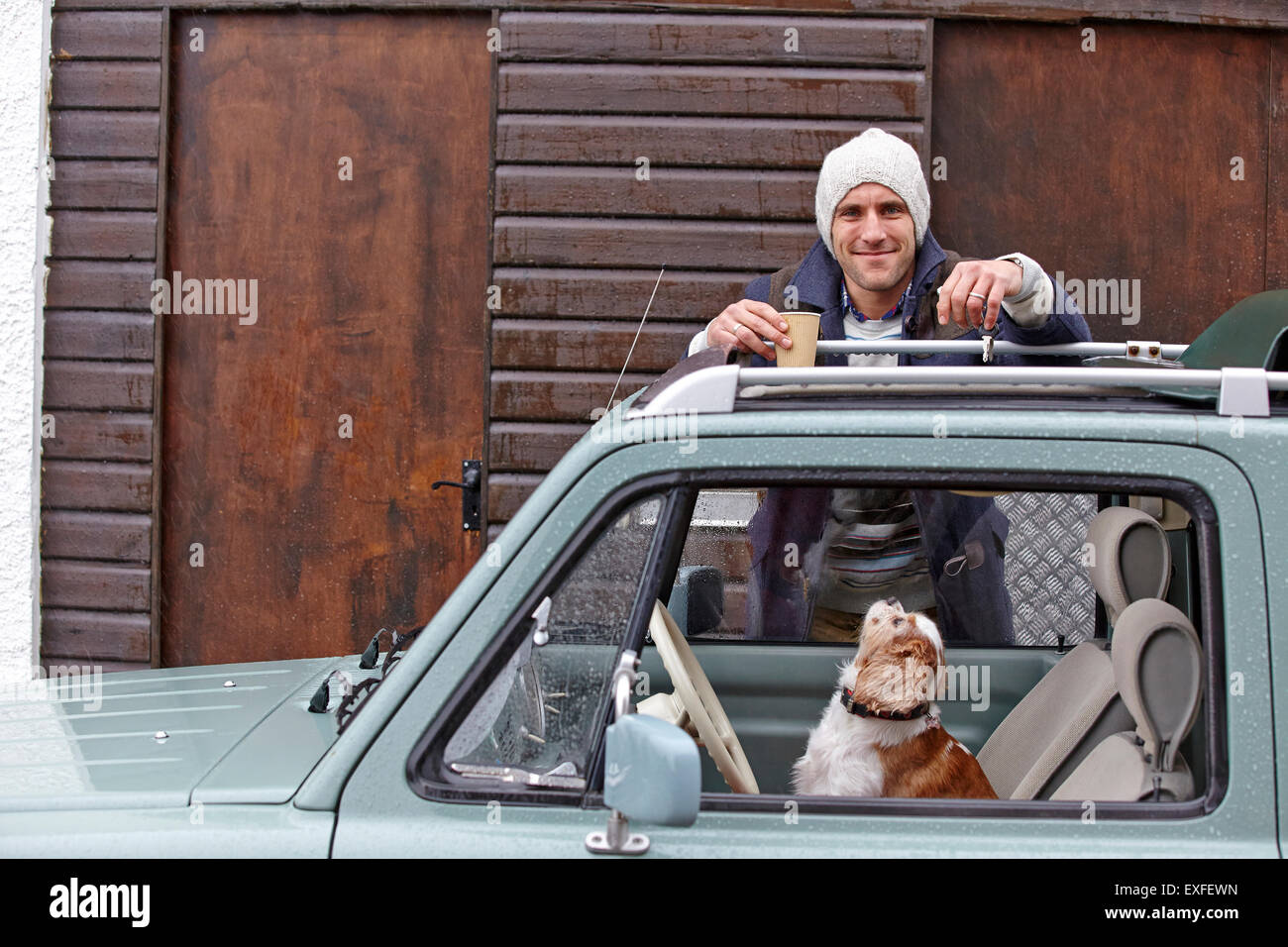 Portrait of mid adult man leaning against van whilst dog looks up Stock Photo