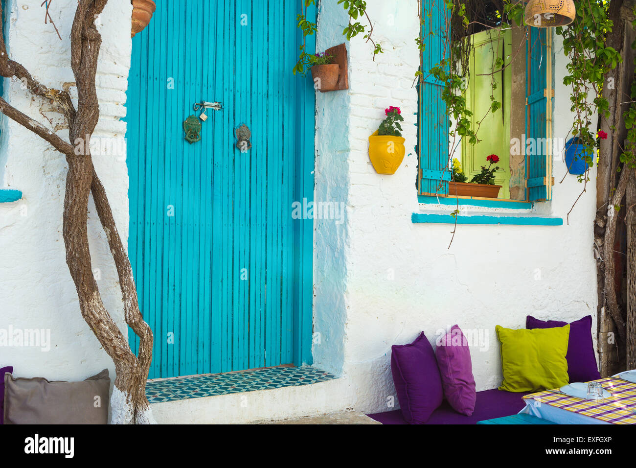 Flowerpots hanged on the  colorful walls and windows of the beautiful old houses in Bozcaada Stock Photo