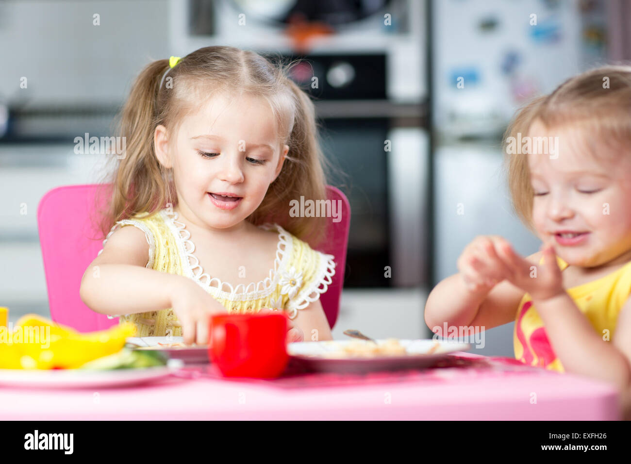 Cute children eat healthy food in nursery or at home Stock Photo