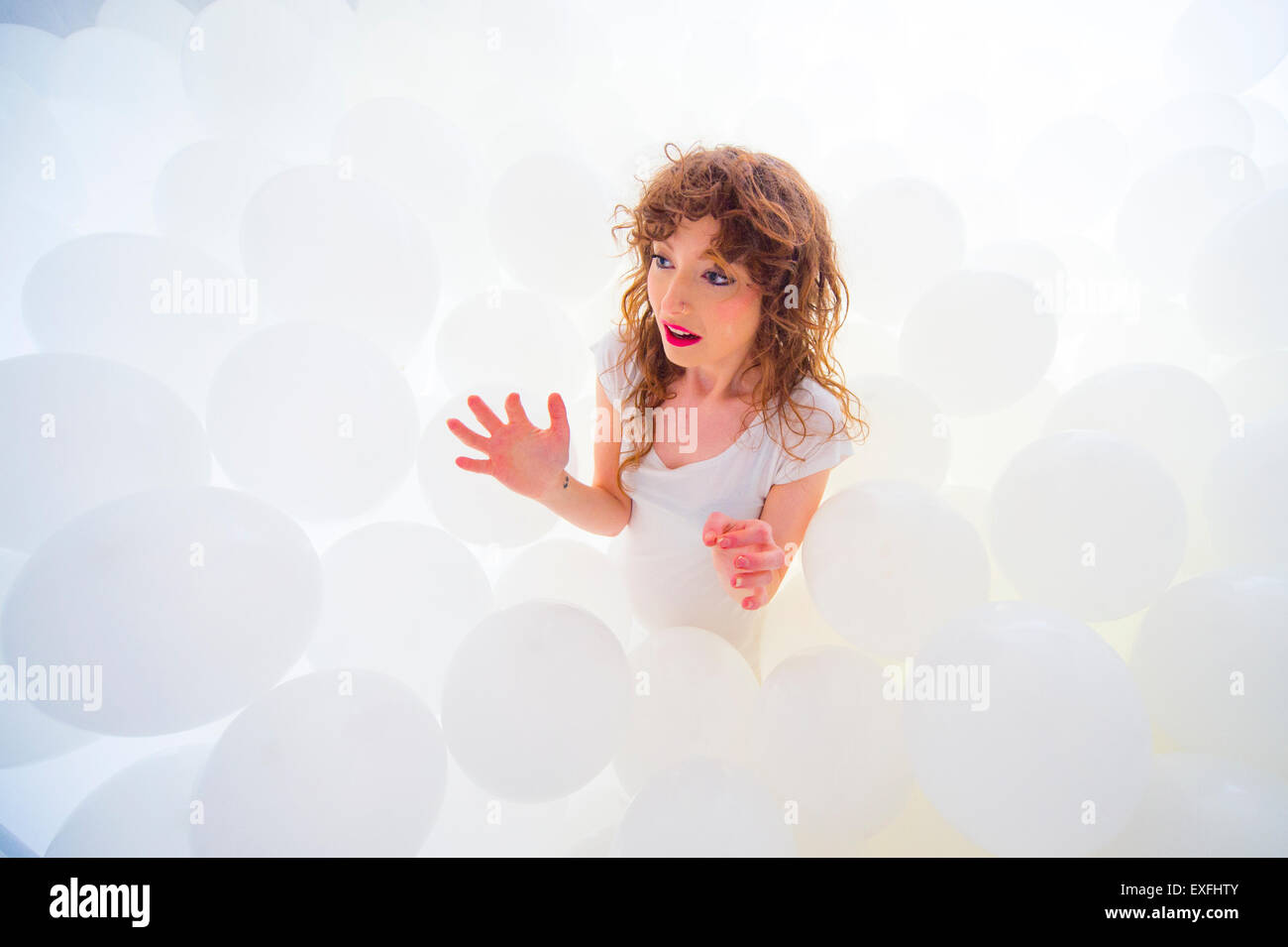 Globophobia a young woman girl alone in a cloud of hundreds of white