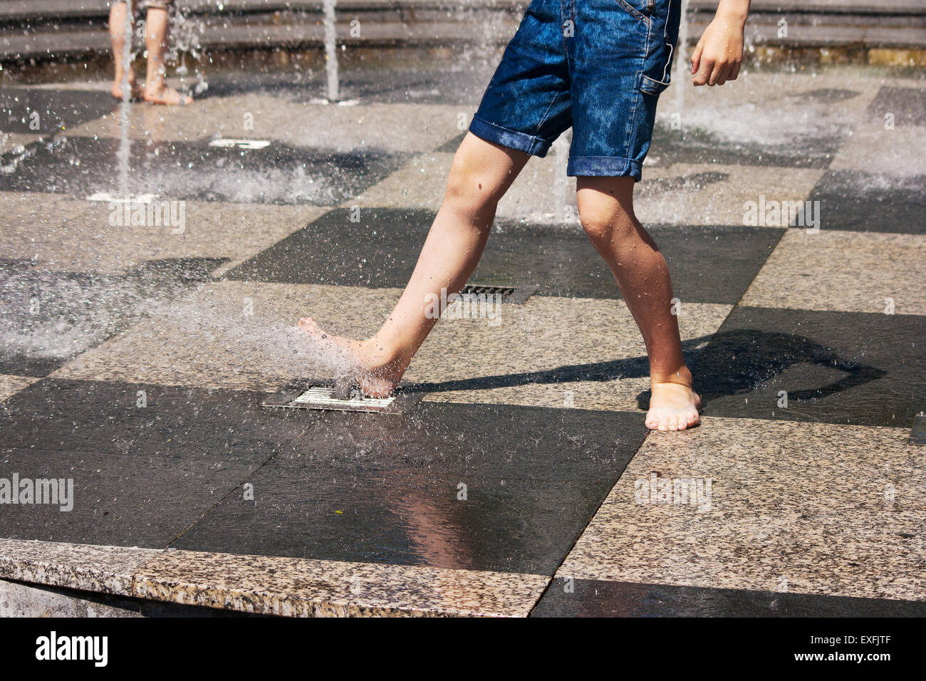 feet of boy in blue jeans playing in the fountain on sunny summer day Stock  Photo - Alamy