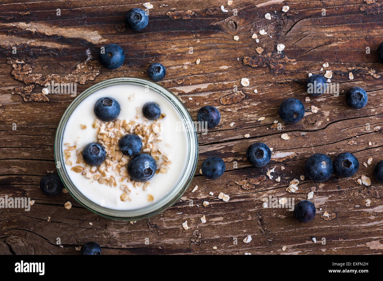 Serving of Yogurt with Whole Fresh Blueberries and Oatmeal on Old Rustic Wooden Table Stock Photo