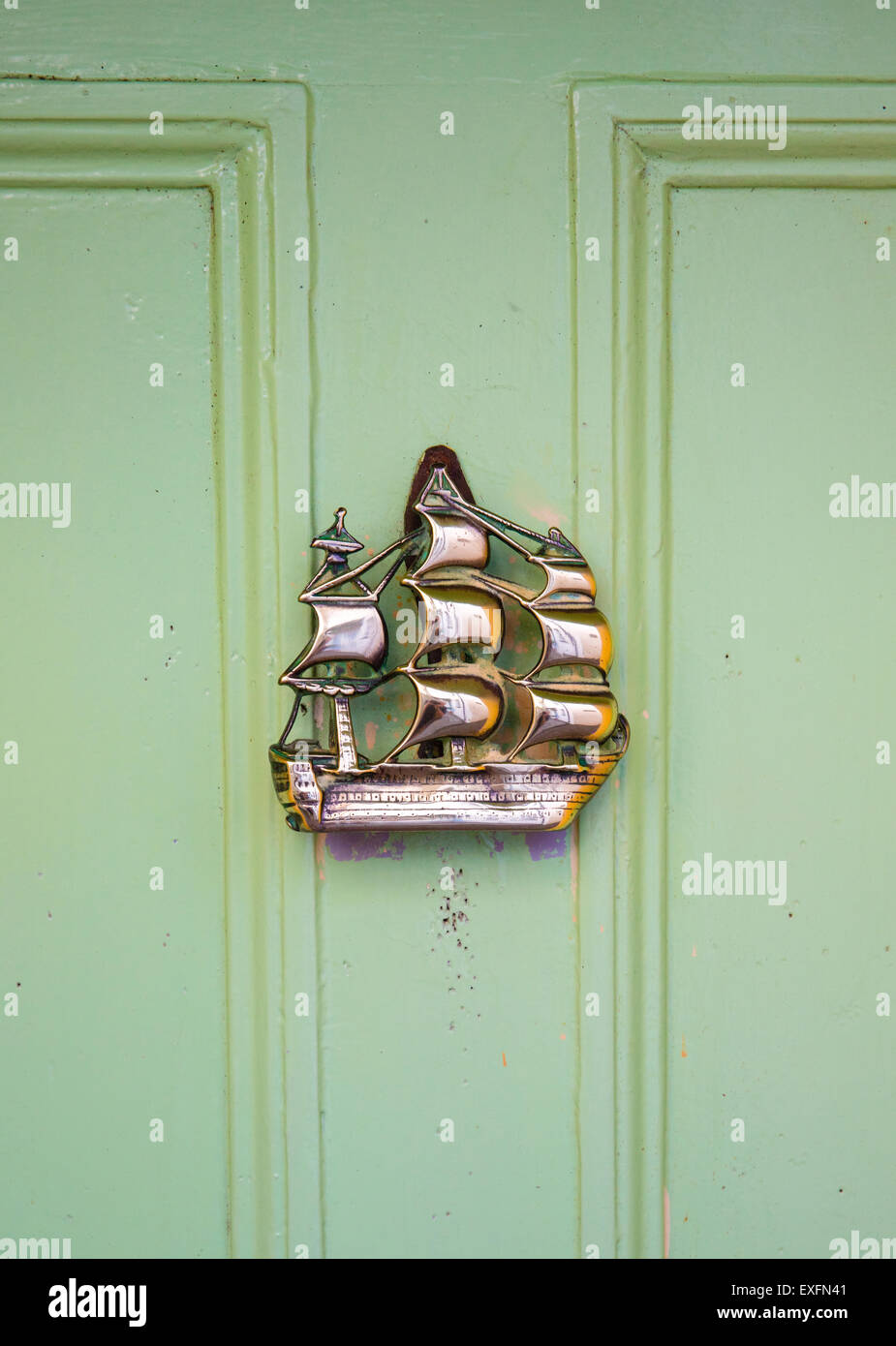 Brass door knocker in the form of a galleon on a green door in the village of Clovelly on the North Devon coast Stock Photo