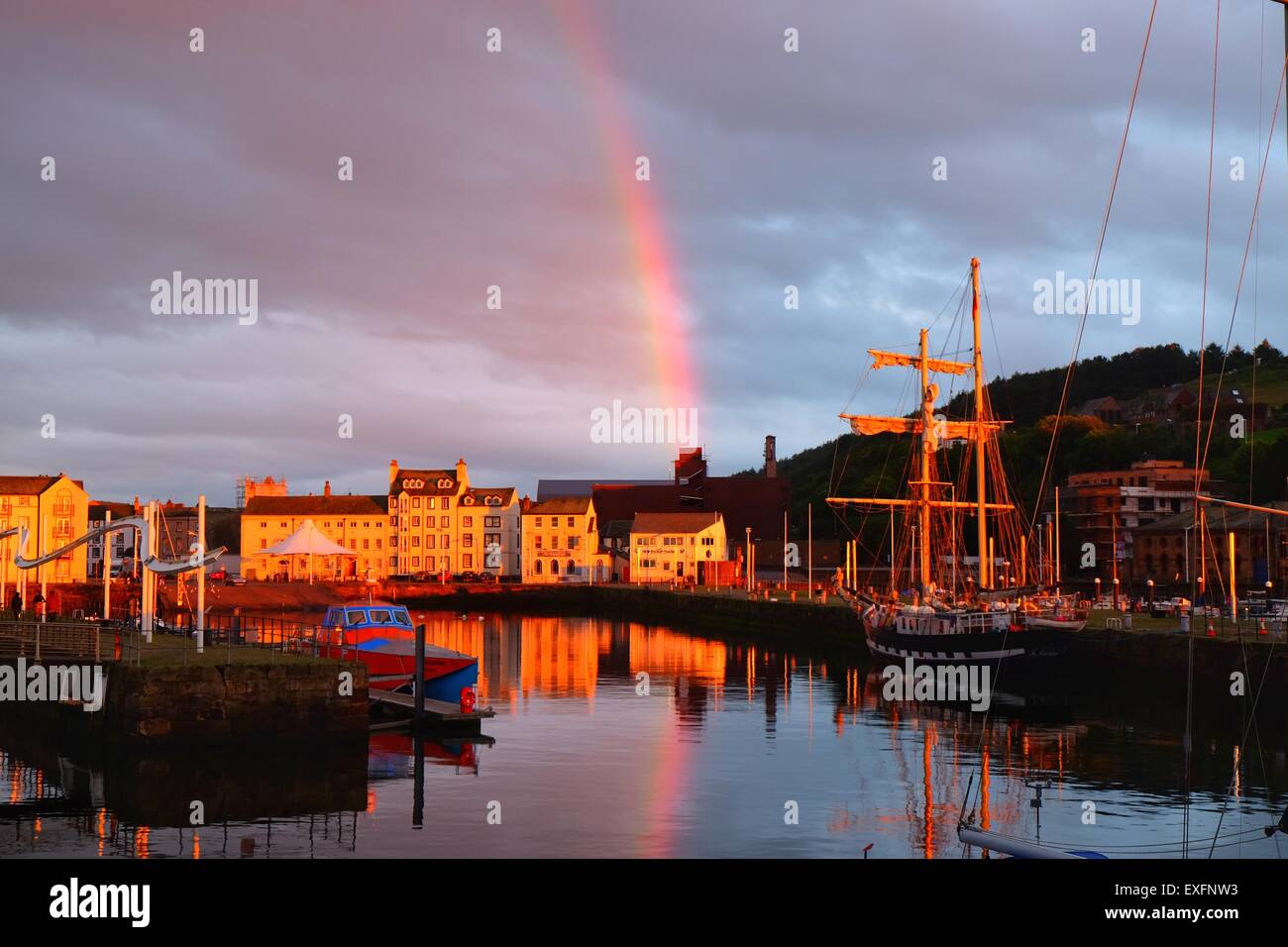 The Lake District, Whitehaven, Cumbria, UK. 13 July 2015. After a muggy day of showers and mist Whitehaven Is treated to a spectacular sunset view and rainbow across the harbour. Credit:  Tom Corban/Alamy Live News Stock Photo