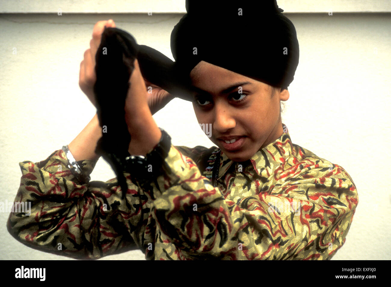 Young Sikh boy tying his turban before school Stock Photo