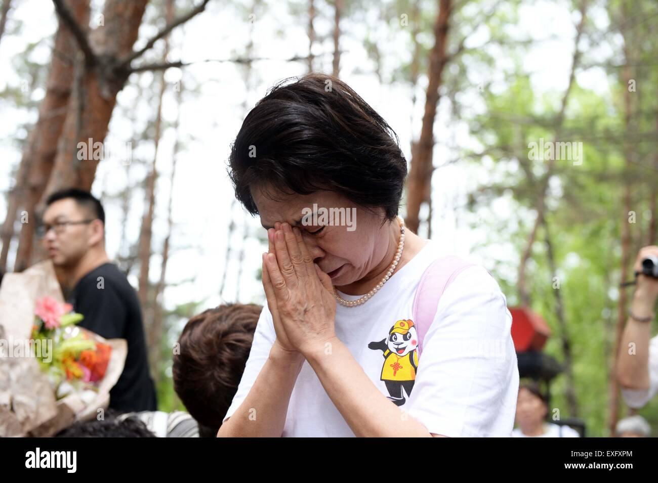 (150714) -- HARBIN, July 14, 2015 (Xinhua) -- Ikeda Sumie, director general of a Tokyo support group for those Japanese returned from China, mourns for adoptive parents in front of a grave in a cemetery to memorize adoptive Chinese parents in Fangzheng County near Harbin, capital of northeast China's Heilongjiang Province, July 13, 2015. A group of 54 Japanese citizens, all now orphans, on Monday paid a visit to the graves of their adoptive Chinese parents here. Abandoned by their birth parents during the hasty retreat at the end of World War II in 1945, the orphans, now over 70 years old, w Stock Photo